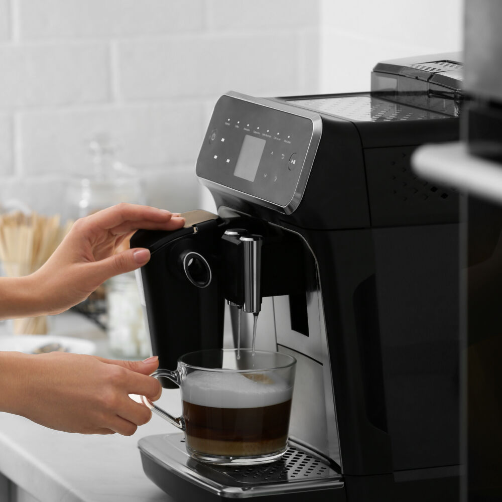 Woman using modern espresso machine for making coffee with milk